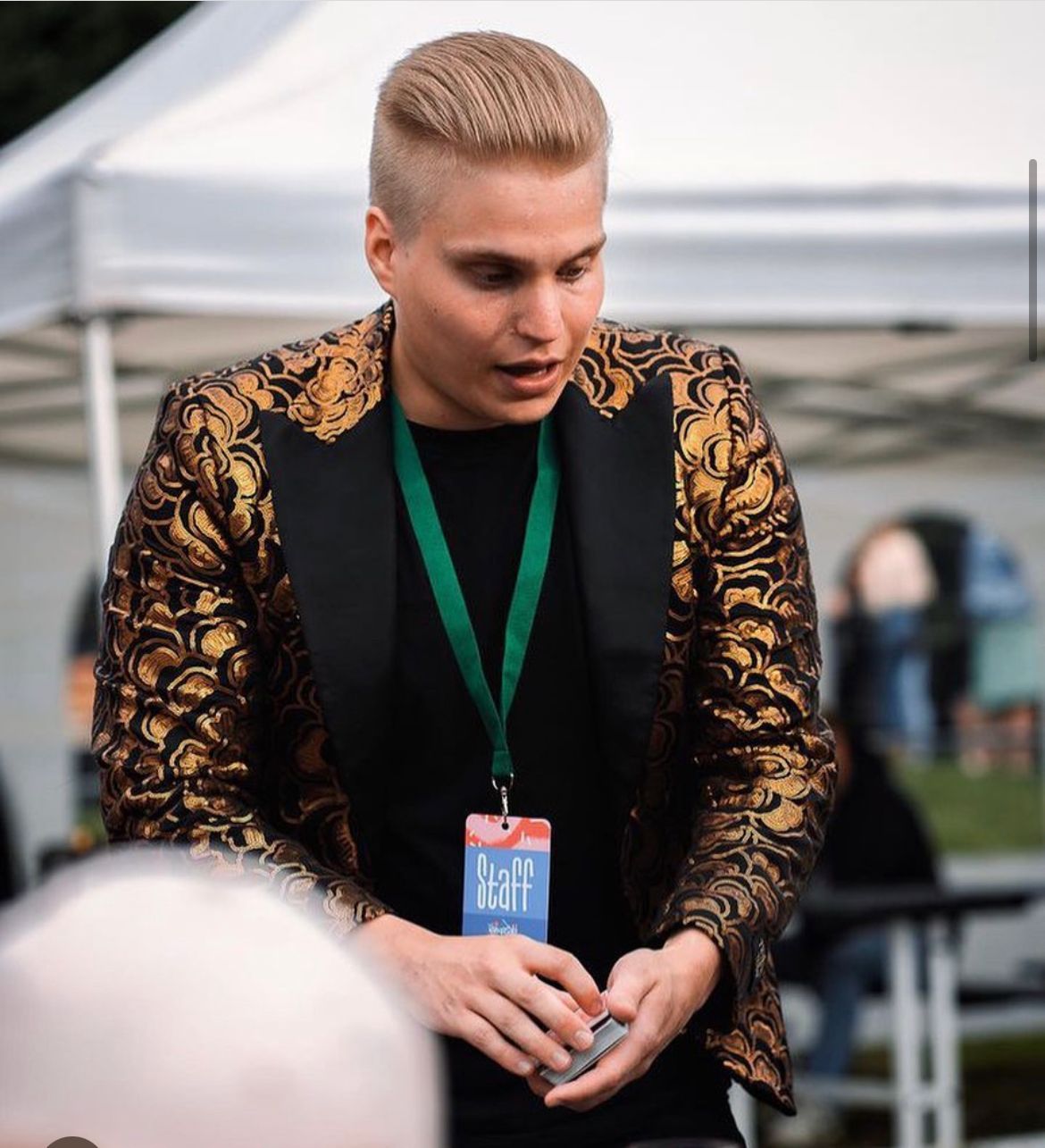 Jari Hynynen näyttämässä korttitemppua ulkotapahtumassa päällään kultainen takki